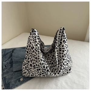 Platliggende canvas draagtas met luipaardprint op wit beddengoed met denim kledingstuk