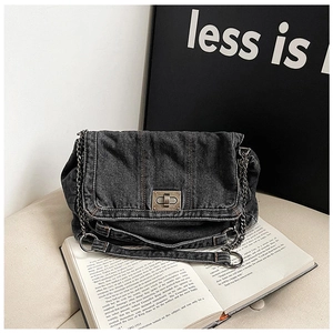 Detail of vintage black denim shoulder bag with retro metal twist lock and chain strap