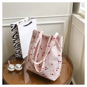 Dettaglio della trama della borsa tote in velluto rosa con stampe di ciliegie rosse