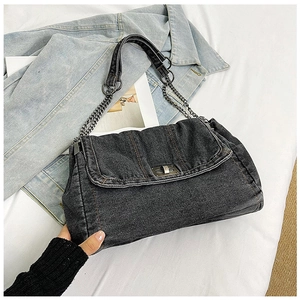 Close-up of black denim shoulder bag featuring a metal chain strap and twist-lock closure