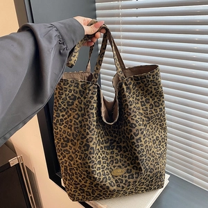 Detailed macro view of the leopard print canvas tote bag featuring a handmade metal logo tag