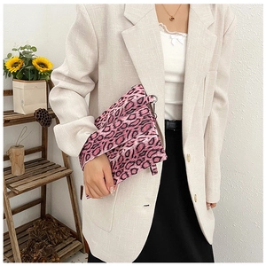 Detail of pink leopard print clutch bag with silver metal ring on model's outfit