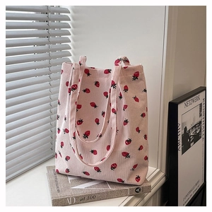 Dettaglio della borsa tote in velluto a coste rosa con stampa di fragole e trama morbida