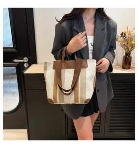 Détail du sac cabas en toile rayée avec coins et poignées en cuir marron renforcé