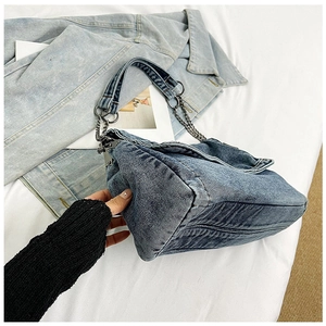 Detail view of washed blue denim tote bag with metal chain and wide shoulder strap