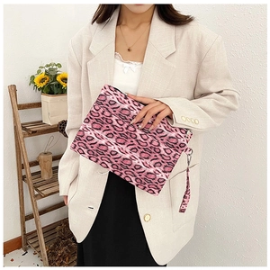 Detail view of pink leopard print clutch bag with wristlet strap held by a model