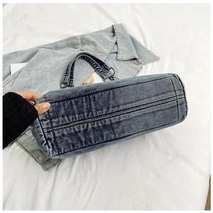 Detailed close-up of reinforced rectangular base on dark blue washed denim tote bag