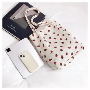 Borsa tote in velluto bianco con fragole accanto a tablet e libri per riferimento taglia