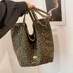 Close-up of leopard print canvas tote bag with a golden handmade metal label detail