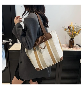 Sac fourre-tout en toile à rayures avec poignées en cuir marron porté par un mannequin ici