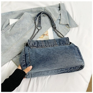 Detail view of vintage blue denim tote bag with metal chain strap and flap closure