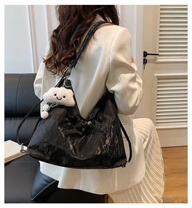 Detail view of black textured tote bag with a white fluffy cloud pendant on a model back