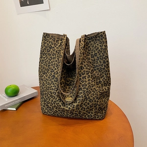 Detail of leopard print canvas tote bag featuring a gold oval handmade metal tag
