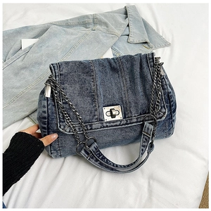 Detailed close-up of blue denim tote featuring silver chain strap and metal swivel lock