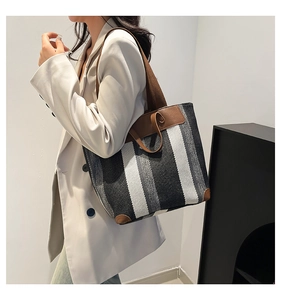 Grand sac cabas en toile rayée avec garniture en cuir porté par un mannequin pour le bureau