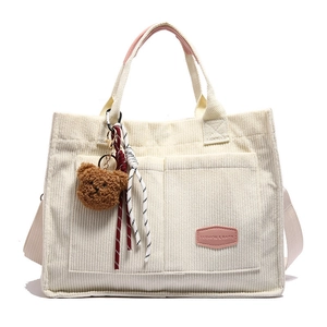 Minimalist beige corduroy tote bag with dual front pockets and plush bear charm decoration