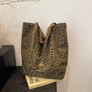 Close-up of leopard print canvas tote bag featuring an oval gold metal logo plate