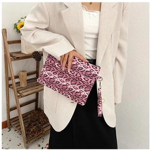Fashionable pink leopard print clutch bag held by model showing compact size and wrist strap