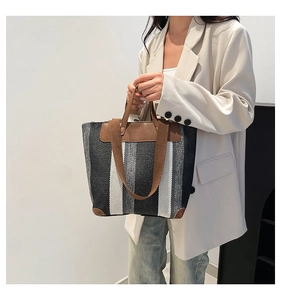 Détail d'un sac cabas en toile à rayures avec finitions et coins renforcés en similicuir brun