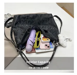Spacious interior of black pleated tote bag holding tablet, umbrella and accessories