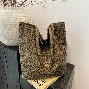 Detailed view of leopard print canvas tote bag with a golden metal logo plate decoration