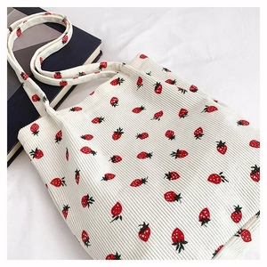 Vista dettagliata della borsa tote in velluto a coste bianco con motivi a fragola rossi