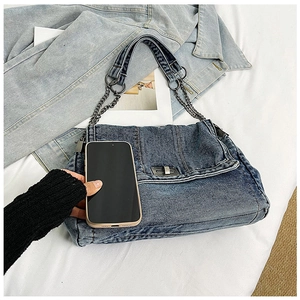 Detail of denim tote bag with metal chain strap and silver twist lock closure