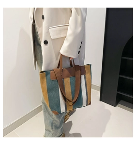 Gros plan du sac cabas en toile rayée avec anses en cuir marron et coutures de précision