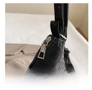 Close-up of smooth silver metal zipper on a black textured faux leather tote bag
