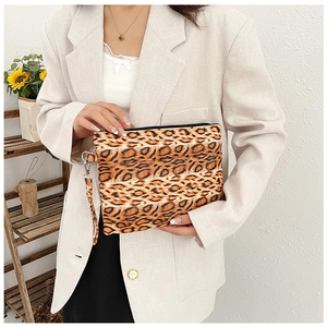Chic leopard print clutch bag held by model featuring sleek texture and wrist strap