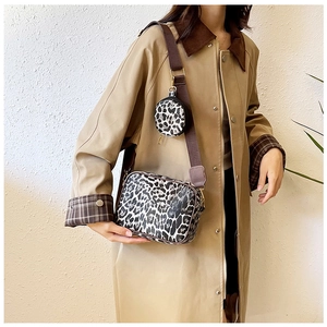 Leopard print crossbody bag set with wide nylon strap shown on a model in a beige coat