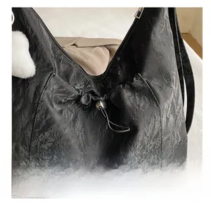 Detailed close-up of drawstring closure on black tote bag with silver hardware and texture