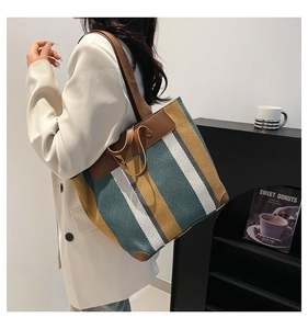 Sac fourre-tout en toile rayée avec détails en cuir marron porté à l'épaule par un mannequin