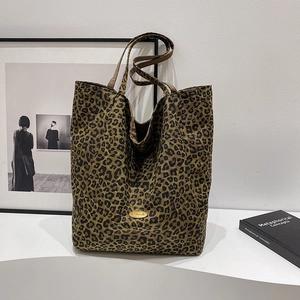 Detailed close-up of a handmade leopard print canvas tote bag with a golden metal logo