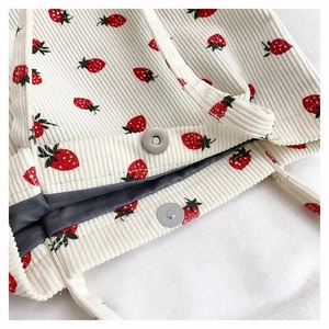 Dettaglio della fibbia magnetica e del motivo a fragola su borsa in velluto