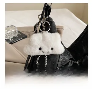 Macro detail of a white fluffy cloud charm with smiling face hanging on a black bag