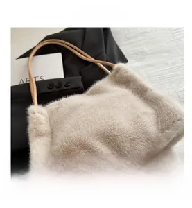 Detail der flauschigen cremefarbenen Kunstpelz-Tasche mit Lederriemen auf schwarzem Blazer
