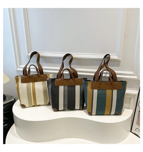 Détail de trois sacs cabas en toile rayée avec poignées en cuir et coins renforcés