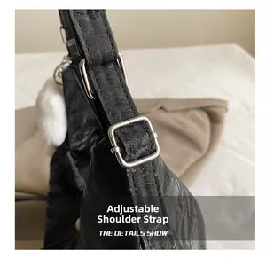Close-up of adjustable strap with silver hardware on black pleated shoulder bag
