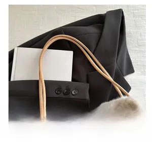 Detailansicht der beigen Plüschtasche mit schmalem kamelfarbenem Ledergriff auf Sakko