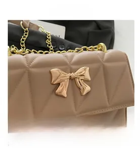 Detail showing beige quilted leather texture and gold bow-shaped metal clasp on the bag