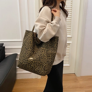 Detail view of leopard print tote bag featuring a high-quality gold metal brand logo plaque