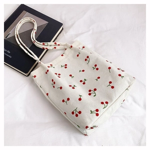 Dettaglio ravvicinato della borsa tote in velluto bianco con stampa ciliegie rosse