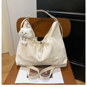 Detail of cream white tote bag with ruched texture and a cute cloud plush charm