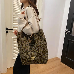 Close-up of leopard print canvas tote bag featuring a metallic handmade label and wide strap