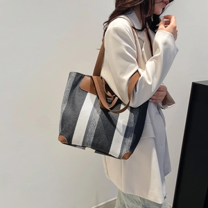 Grand sac cabas à rayures avec finitions en cuir marron porté par un mannequin de profil