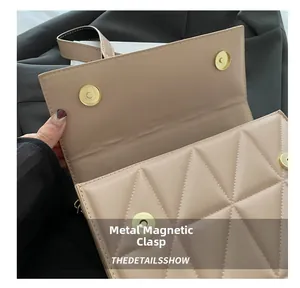 Detail view of the double magnetic gold hardware buckle on a quilted crossbody bag