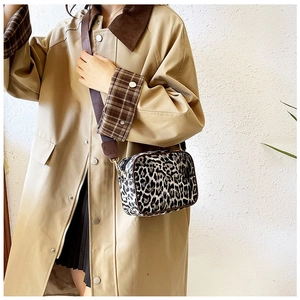 Leopard print crossbody camera bag with brown trim and wide nylon shoulder strap on model