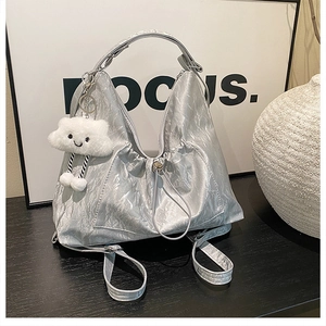 Detail of silver metallic tote bag featuring pleated texture and cute cloud charm accessory