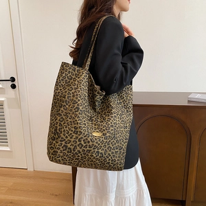Detailed close-up of large canvas leopard print tote bag with gold logo and shoulder strap
